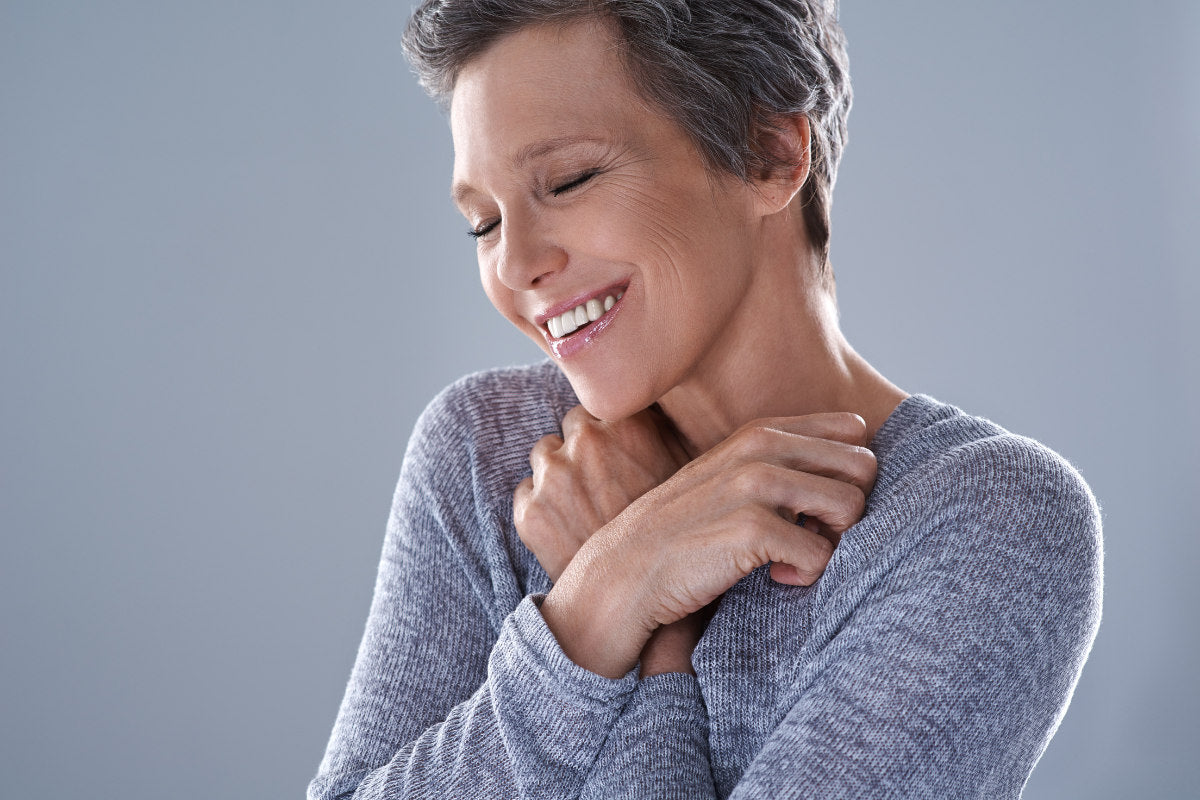mature woman hugging herself, smiling, showing self-love