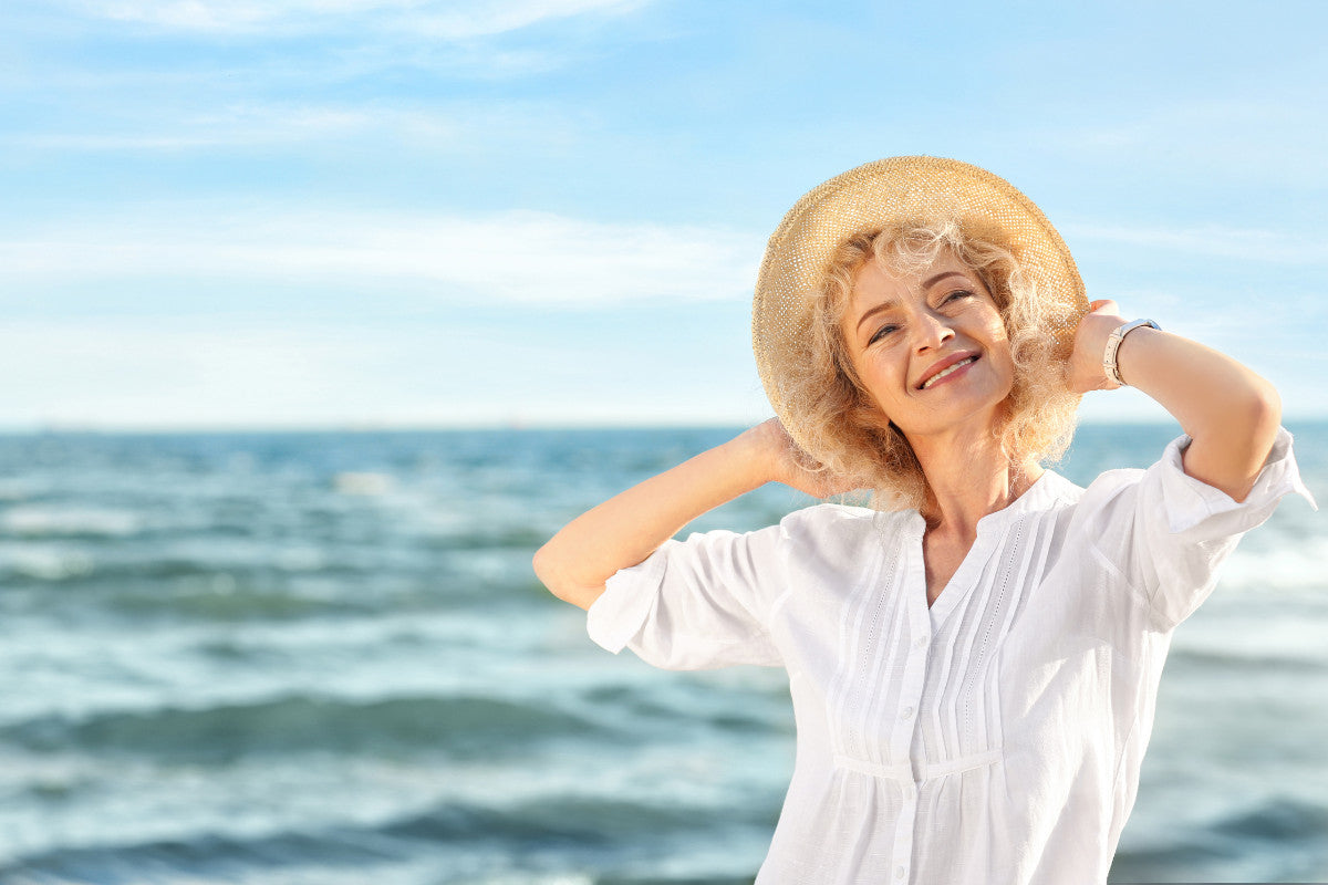 Senior woman in a sunhat enjoying the sun on the beach.