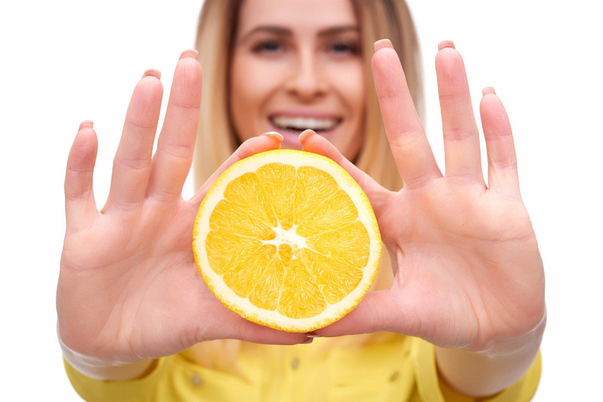 woman holding orange slice in front of her with both hands