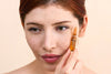 young woman looking down past the camera, holding up a Vitamin C Ampoule next to her cheek and eye