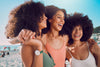 three women standing together and laughing on the beach