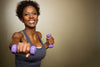mature woman smiling and holding up purple dumbbells