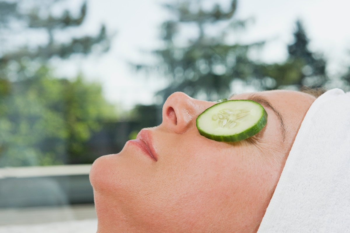 close-up of woman relaxing with cucumber slices over her eyes.