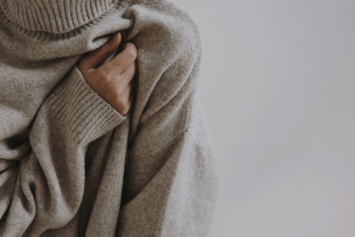 from head to mid-waist, close-up of woman wearing a gray turtleneck sweater.