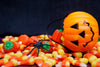 jack-o-lantern candy basket laying on top a pile of candy corn.