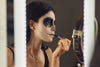 woman applying Halloween makeup over her lips while looking in a mirror