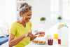 mature woman smiling as she spreads jelly on slices of toast