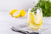 glass of lemon water sitting on a folded gray napkin.