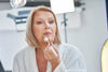 older woman applying foundation to her face.