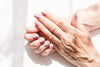 mature woman's hands with light pink nail polish