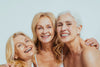 Three senior women smiling and hugging each other.