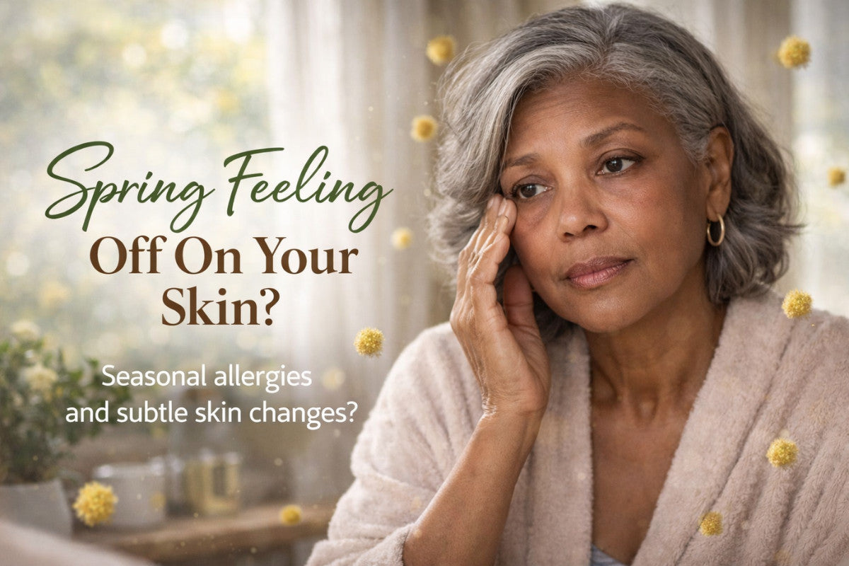 Mature woman gently touching under-eye area in soft morning light, with pollen in the air suggesting seasonal skin sensitivity.