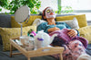 woman laying on couch with a blanket, face mask, and cucumbers on her eyelids, relaxing