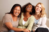 three mature women sitting on a couch and laughing together