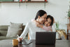 mother working on her computer while hugging her child